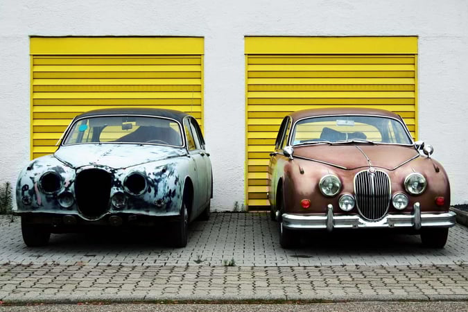 Two differently painted cars parked next to each other 