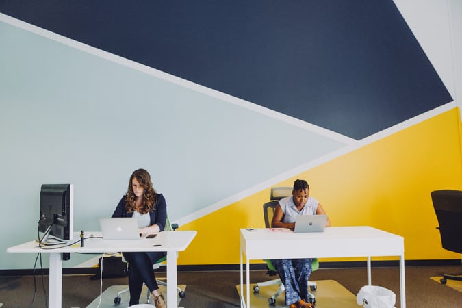 Two women working at separate desks signifying data silos