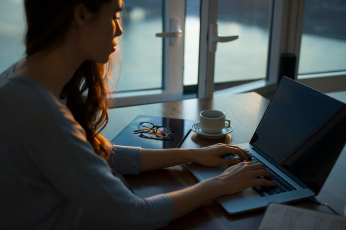 Woman working on a laptop in silhouette