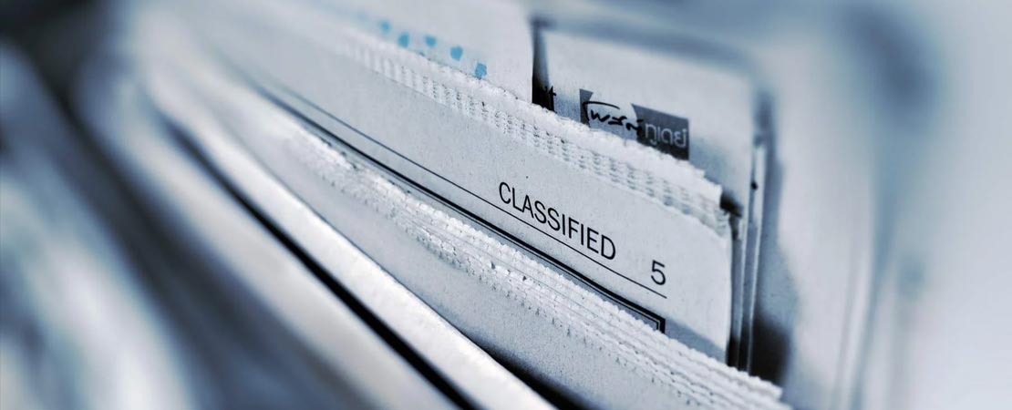 stack of newspapers focused on the word classified - illustrating data anonymization